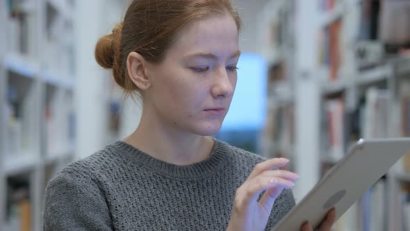 Redhead Woman Browsing Internet on Tablet at Work alt