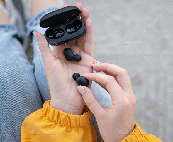 Female hands touching a portable gadget headphones.