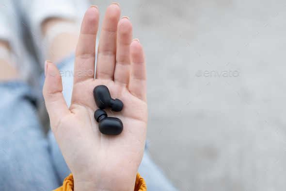 Female hands holding a portable gadget black wireless headphones