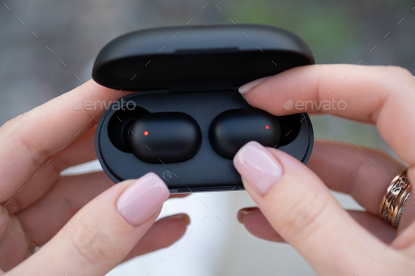 Female hands touching a portable gadget headphones.