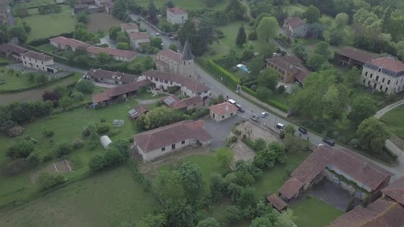Aerial view of bell tower church french village countryside green meadows trees Sarremezan France