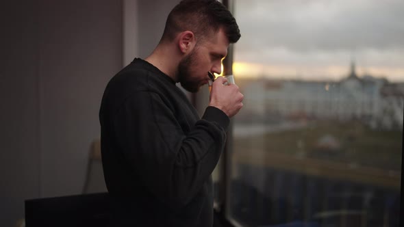 A Man Drinks Black Tea Near the Window Overlooking the Sunset