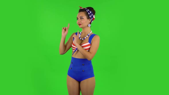 Beautiful Girl in a Swimsuit Is Talking and Pointing Side Hand for Something, Copy Space. Green alt