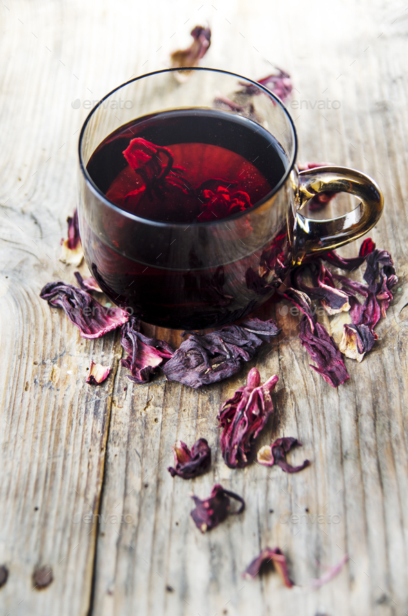 Hibiscus tea in teacup with dry hibiscus flower leaves. Stock Photo by