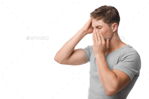 Upset young caucasian man suffering from headache, runny nose, feeling unwell