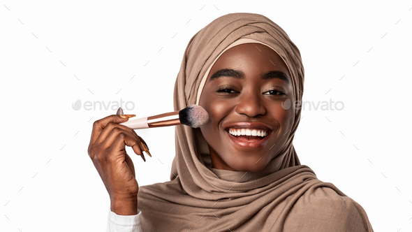 Portrait of happy muslim black woman with makeup brush