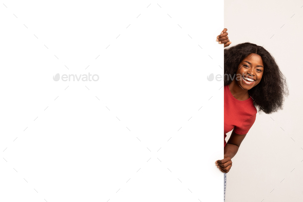 Excited Black Young Lady Peeking Out Of Blank Advertisement Board