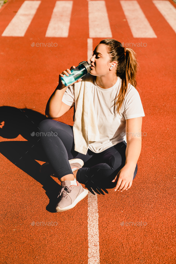 Athlete drinking water after jogging running doing workout training yoga class outdoors in stadium