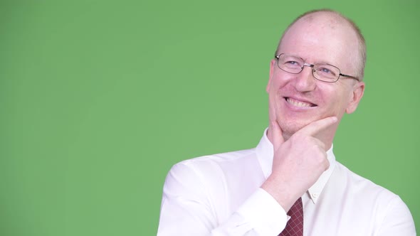 Happy Mature Bald Businessman Thinking alt