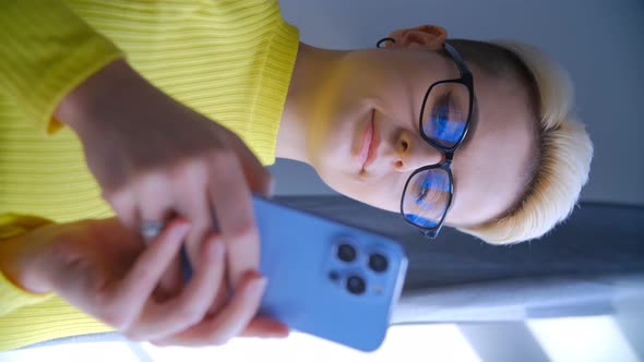 Stylish tom boy female using modern smartphone in vertical 4k video clip alt