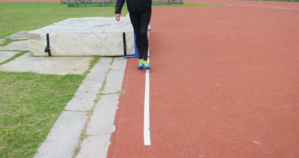 Low section of female athlete measuring high jump field with footstep 4k alt