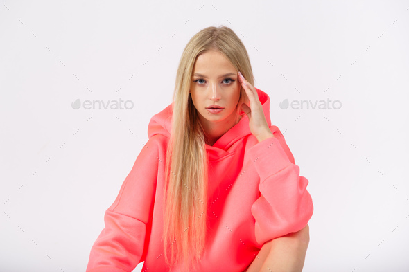 Young pretty woman wearing pink hoodie and white cycling shorts posing on white background