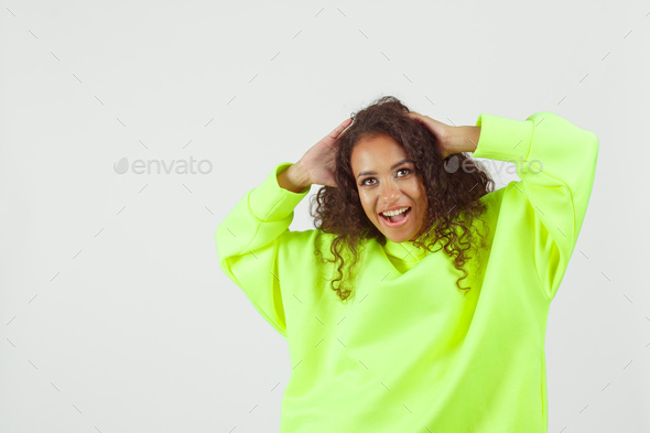 Young pretty african woman wearing green hoodie and white cycling shorts posing on white background