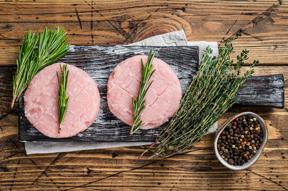 Raw burgers patty from organic chicken and turkey meat with thyme and rosemary.