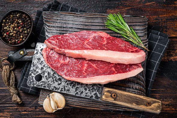 Raw top sirloin cap beef meat steaks on butcher board with meat cleaver ...