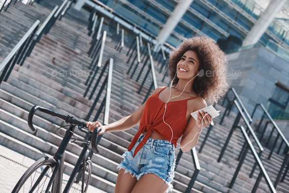 Young woman in earphones free style on the street walking near s