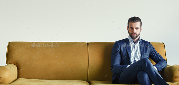 Waiting for a meeting...Well-dressed young and successful businessman is sitting on sofa at office - Stock Photo - Images