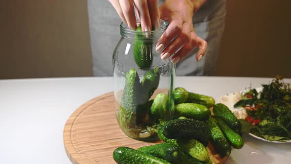 Woman Puts Spices and Fresh Cucumbers in a Glass Jar Preparing for Canning alt
