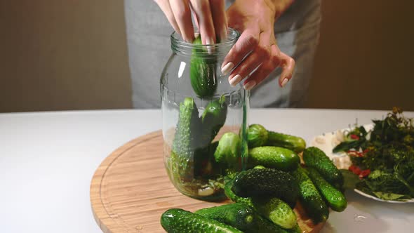 Woman Puts Spices and Fresh Cucumbers in a Glass Jar Preparing for Canning