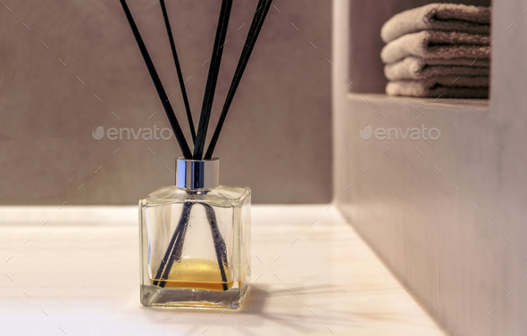 Reed diffuser in a bathroom, black sticks in a glass bottle, modern design  spa interior detail. Stock Photo by rawf8