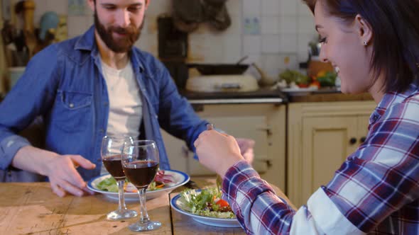 Young couple talking while having meal in kitchen alt