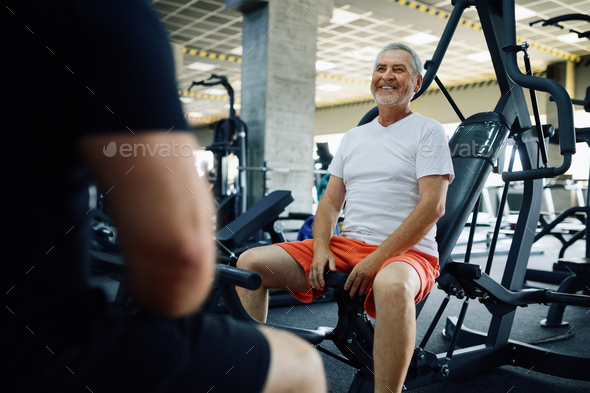 Elderly man poses on exercise machine in gym