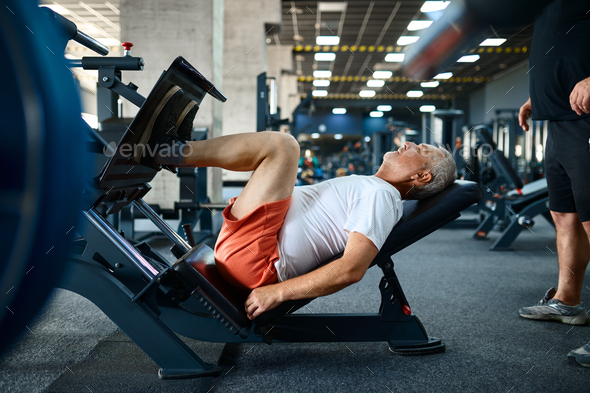 Elderly man on exercise machine in gym