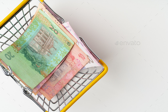 Toy shopping cart with Ukrainian hryvnia money. Purchasing power and living wage concept - Stock Photo - Images