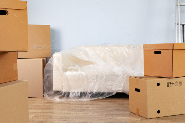 Packed household stuff in boxes and packed sofa for moving