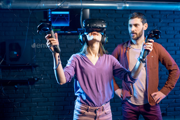Woman trying virtual reality with man assistant