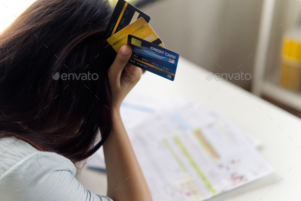 stressed young Asian woman hands holding the head with dummy credit cards
