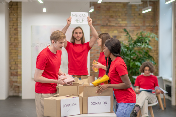 Young volunteers in red tshirts distributing donations in a sorting center