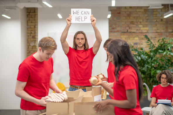 Young volunteers in red tshirts distributing donations in a sorting center