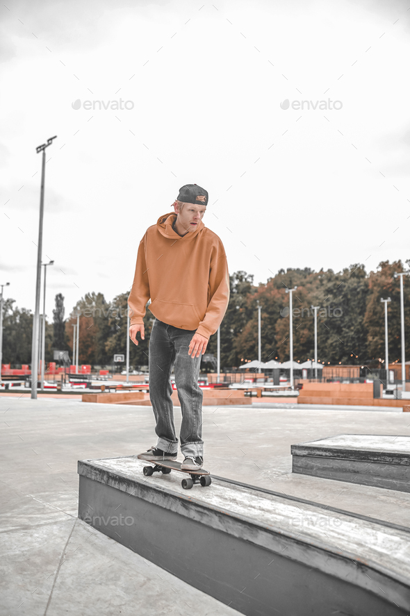 Guy on skateboard riding bollard in skatepark