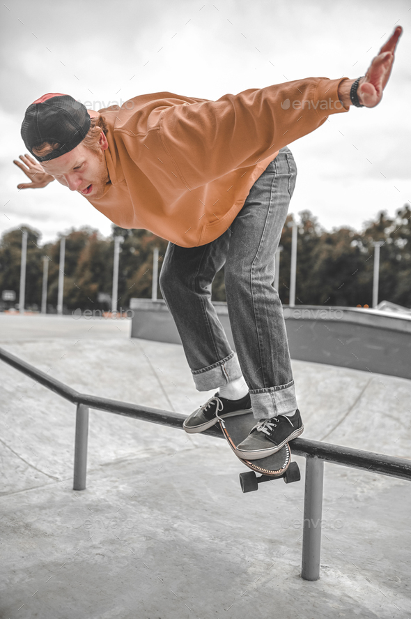 Guy on skateboard flying over railing in skatepark