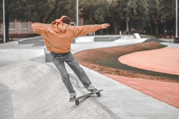 Cheerful guy on skateboard sliding down