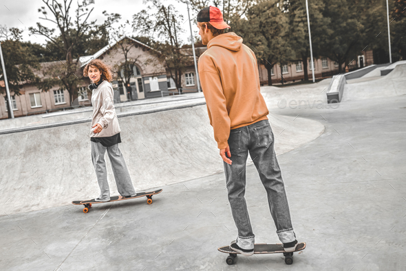 Girl and guy on skateboards sliding in skatepark