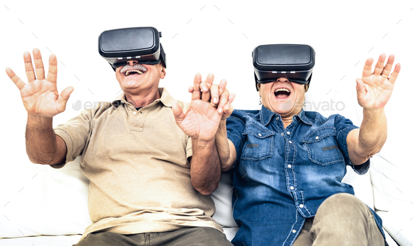 Senior mature couple having fun together with virtual reality headset sitting on sofa - Stock Photo - Images