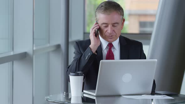 Mature businessman talking on cell phone in office lobby