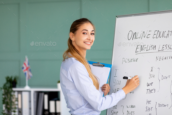 Online foreign languages school. Cheerful teacher writing on blackboard, teaching English on web