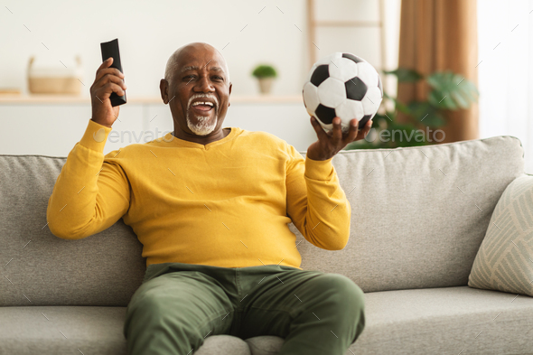 Senior African Man Watching Sport On TV Celebrating Victory Indoor