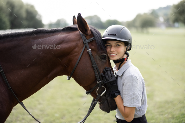 Female horseman hugging head of Thoroughbred horse - Stock Photo - Images