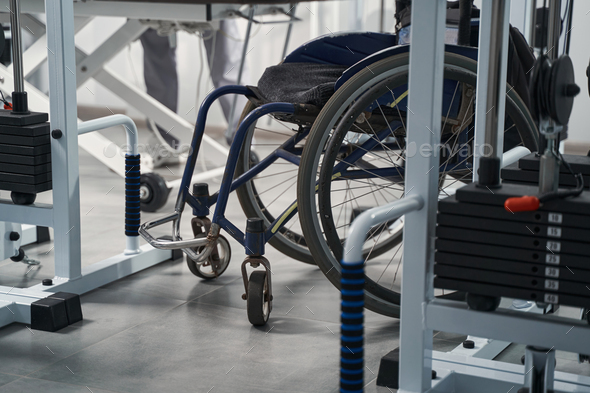 Empty wheelchair standing at physiotherapy gym room close up. Interior