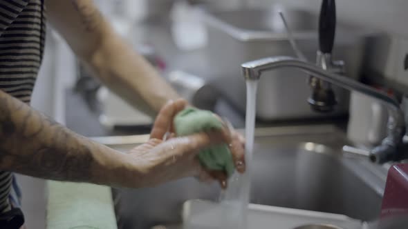 Tattooed Man Wrings Out Washcloth and Turns Faucet Off Close View alt
