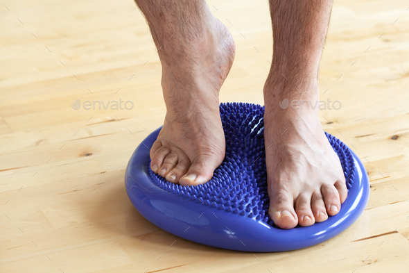 man doing flatfoot correction gymnastic exercise balancing on massage cushion at home - Stock Photo - Images