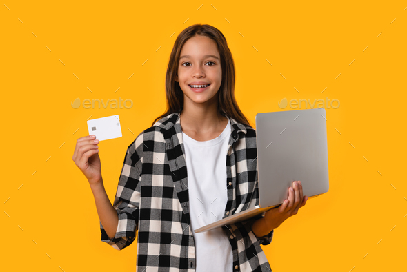 Happy caucasian teenager girl student using laptop for paying with credit card for bills loan debt