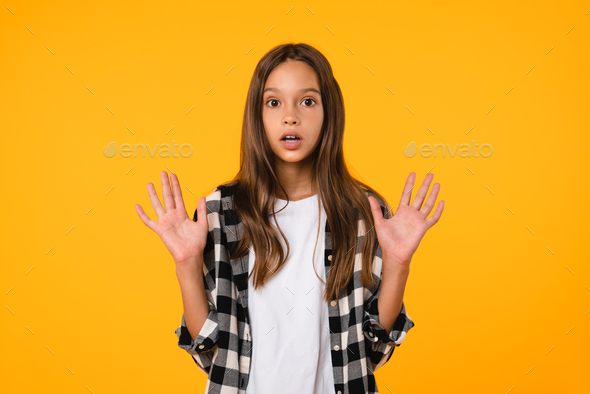Shocked girl teenager schoolkid worrying, scared, crying isolated in yellow background.
