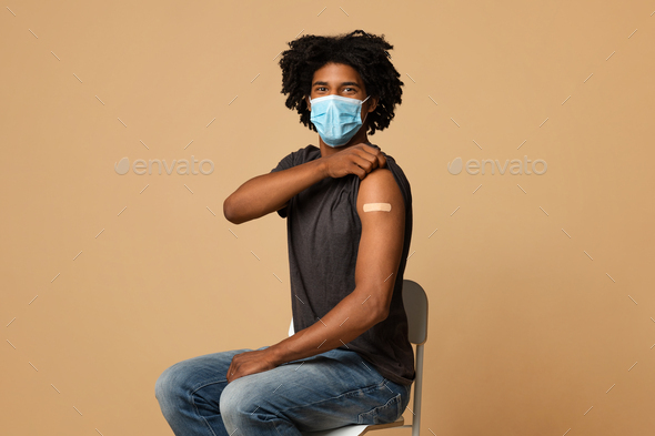 Flu Vaccination. Young Black Man In Medical Mask Showing Arm With Plaster