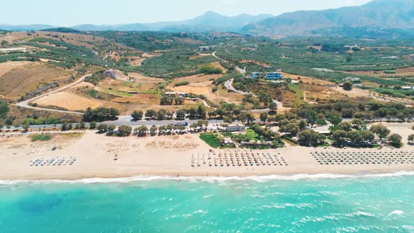 Aerial View of Sea Shore Beach with Umbrellas, Car Road and Mountains in Greece
