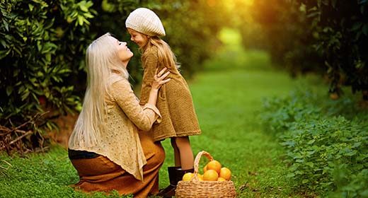 Mom and daughter pick oranges in the green garden